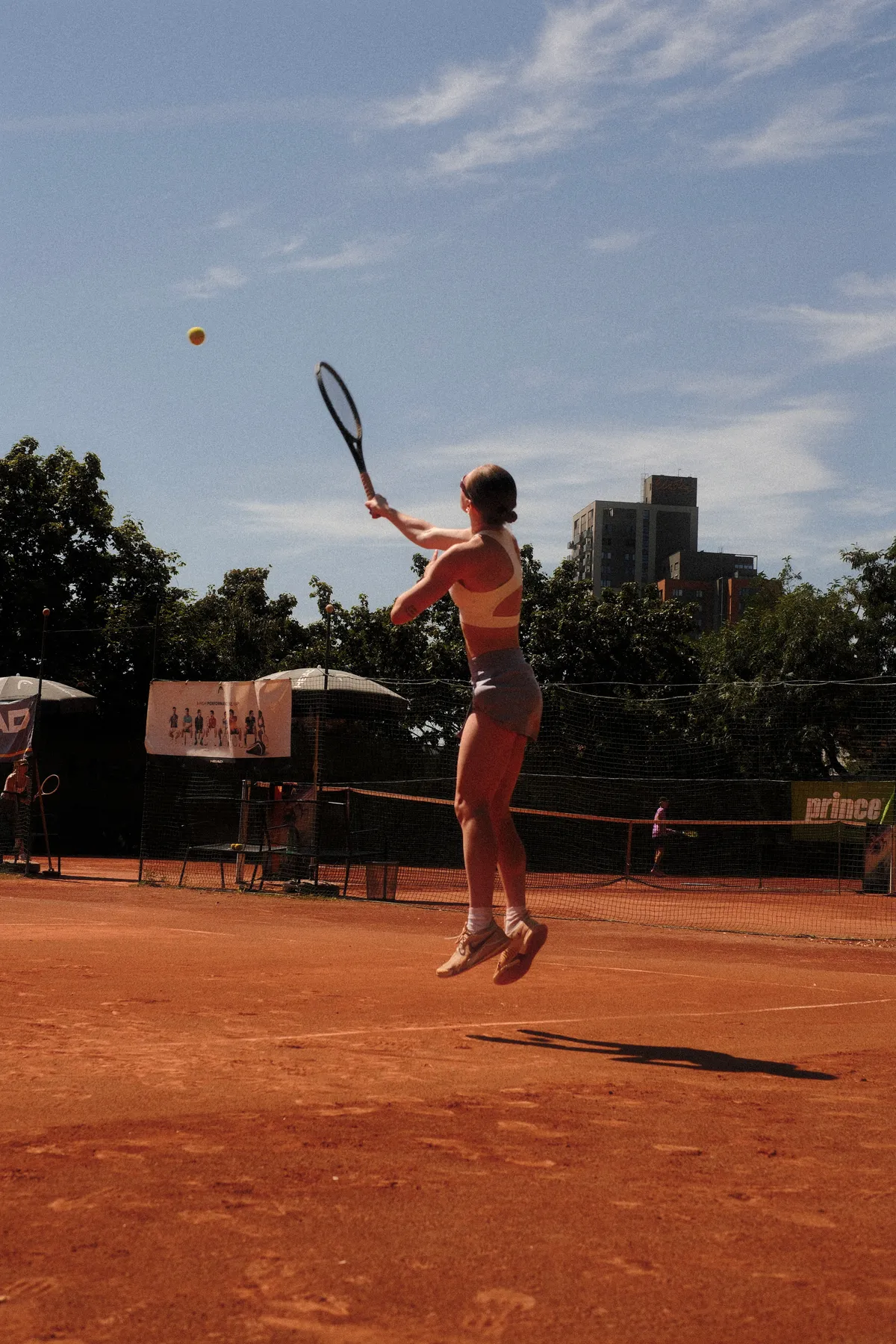 Hráčka při podání na antukovém kurtu na turnaji Your Tennis Club